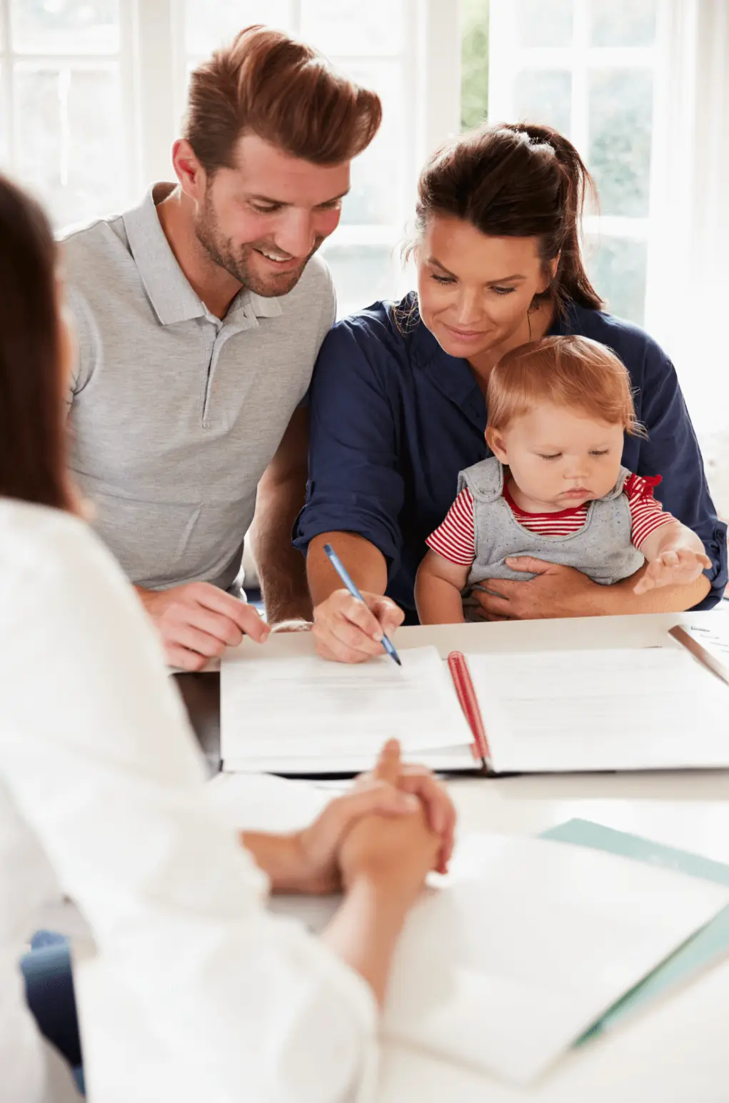 Family signing documents at a table